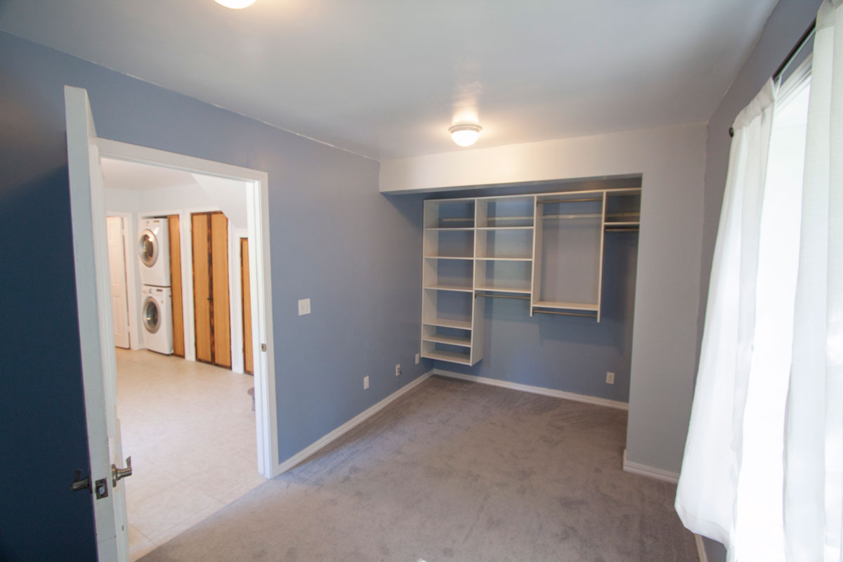 	The closet area at the end of the bedroom has very efficient storage shelves.